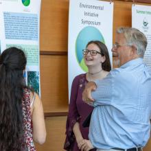 Students discuss their poster with faculty